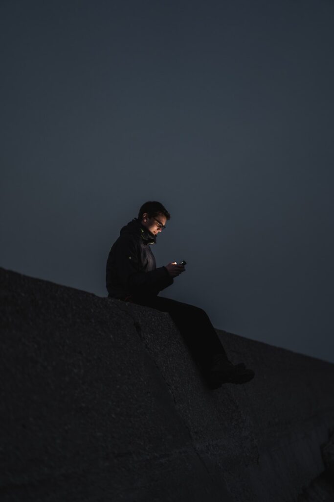 man in black jacket sitting on the edge of a building