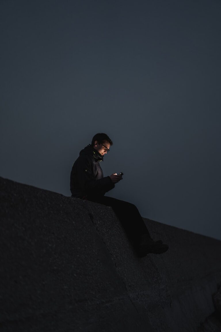 man in black jacket sitting on the edge of a building
